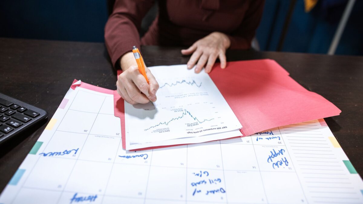 Kalender, Unterlagen und Taschenrechner auf einem Schreibtisch zur Finanzplanung