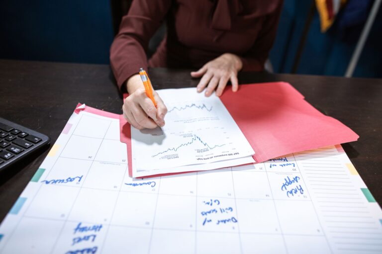 Kalender, Unterlagen und Taschenrechner auf einem Schreibtisch zur Finanzplanung