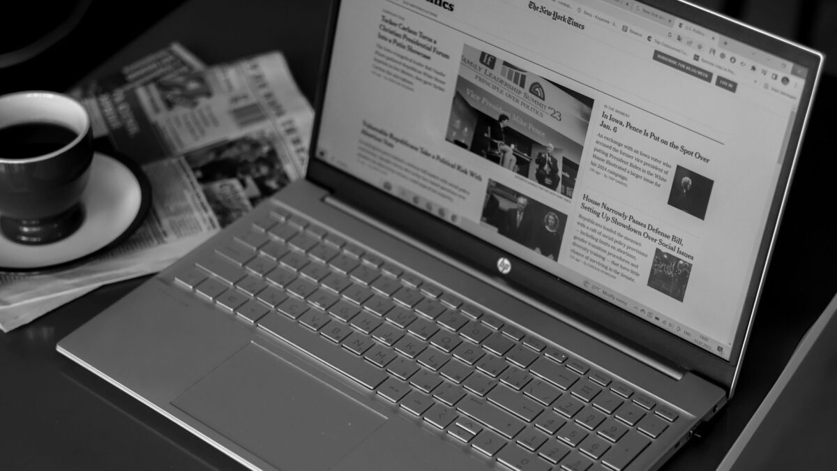 Redaktionsschreibtisch mit Zeitungen, Notizblock und Laptop