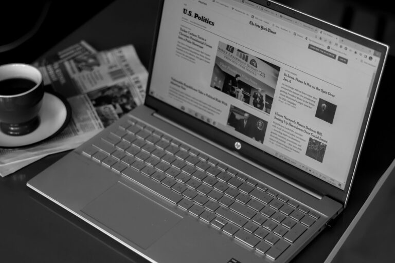Redaktionsschreibtisch mit Zeitungen, Notizblock und Laptop